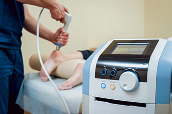 Shock wave therapy. The magnetic field, rehabilitation. Physiotherapist doctor performs surgery on a patient's heel